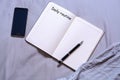 Open notepad with black pen with the inscription and place for text lies on the bed with a smartphone. The concept of freelancing