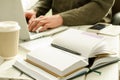 Open notepad with black pen on work-table. Paper cup of coffee, office stuff, laptop and working man on background Royalty Free Stock Photo