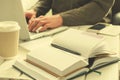 Open notepad with black pen on work-table. Paper cup of coffee, office stuff, laptop and working man on background Royalty Free Stock Photo