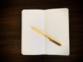 An open notepad with a golden pen on a wooden background.