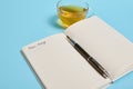 Open notepad with word Dear Diary and an ink pen next to a tea cup on blue background with copy space Royalty Free Stock Photo