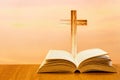 Open old bible on a wood table with blurred cross & colourful clouds and sky as background Royalty Free Stock Photo