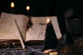 Open old book with magic spells, runes, black candles on witch table. Occult, esoteric, divination and wicca concept