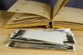 An open old photo album wrapped in yellow velvet and a stack of black and white photos in the foreground Royalty Free Stock Photo