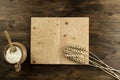 Open old vintage book on the aged wooden background. Kitchen utensils, ears of wheat, flour in a pot. Royalty Free Stock Photo