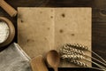 Open old vintage book on the aged wooden background. Kitchen utensils, ears of wheat, flour in a pot. Royalty Free Stock Photo