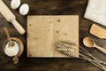 Open old vintage book on the aged wooden background. Kitchen utensils, ears of wheat, flour in a pot. Royalty Free Stock Photo