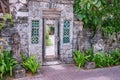 Open old wooden entry doors in stone wall with two traditional Balinese guard statues, street photo