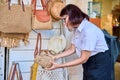 Outdoor showcase with woven knitted bags. Woman shopper choosing a bag.