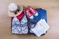 Open packed suitcase with female summer clothes and accessories, bathing suit, hat, sunglasses, sneakers, white shirt on wooden fl Royalty Free Stock Photo