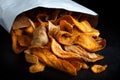 Open packet of fried parsnip and carrot chips on black. Royalty Free Stock Photo