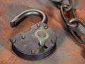 Open padlock with key and an old rusty link chain on an orange background Royalty Free Stock Photo