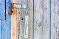 Open padlock on a scuffed wooden door with weathered cracks of blue and beige colors of old country house Royalty Free Stock Photo