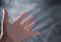 Open palm with five fingers in fume, filtered. Human arm in natural light with shadows, toned. Help gesture. Opacity concept.