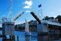 An open pedestrian draw bridge opens to allow a small sailboat to cruise through