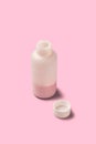open pink medicine bottle with cap pink background Royalty Free Stock Photo