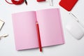 Open pink paper notebook, power bank with cable, red smartphone, headphones, wireless mouse Royalty Free Stock Photo