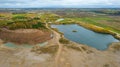 Open pit gravel mining site with lake or pond of unusual shape and beautiful autumn nature, gravel piles photographed with drone Royalty Free Stock Photo