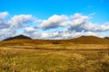 Open plain with sparse trees and yellowish green grass with autumn hills against blue sky Royalty Free Stock Photo