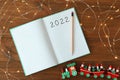 Open planner, pencil, Christmas lights and toy train on wooden background, flat lay. 2022 New Year aims Royalty Free Stock Photo