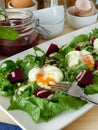 Open poached egg on a green salad and pieces of beetroot