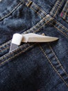 Open pocket knife in blue jeans