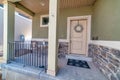 Open porch with railings at house facade with front door decorated with wreath