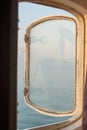 An open porthole on a ship with a reflection of a boat hanging on cables Royalty Free Stock Photo