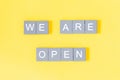 We are open quote, welcome sign for business or caffe, wooden letters on yellow background