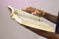 The open Qur& x27;an is held by the hand holding the prayer beads & x28;tasbih& x29;. The Qur& x27;an is the holy book of Islam Royalty Free Stock Photo