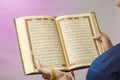 The open Quran is held by the hand holding the prayer beads. The Quran is the holy book of Islam Royalty Free Stock Photo