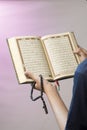 The open Qur& x27;an is held by the hand holding the prayer beads & x28;tasbih& x29;. The Qur& x27;an is the holy book of Islam Royalty Free Stock Photo