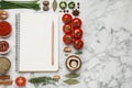 Open recipe book and different ingredients on white marble table, flat lay. Space for text Royalty Free Stock Photo