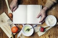 Open recipe book in the hands of an elderly woman