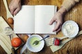 Open recipe book in the hands of an elderly woman