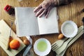 Open recipe book in the hands of an elderly woman