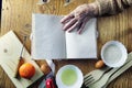 Open recipe book in the hands of an elderly woman