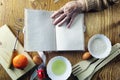 Open recipe book in the hands of an elderly woman