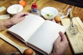 Open recipe book in the hands of an elderly woman