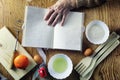 Open recipe book in the hands of an elderly woman