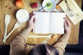 Open recipe book in the hands of an elderly woman