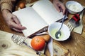 Open recipe book in the hands of an elderly woman