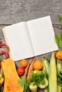 Open recipe book with set of raw organic vegetables on vintage wooden table Royalty Free Stock Photo