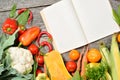 Open recipe book with set of raw organic vegetables on vintage wooden table Royalty Free Stock Photo