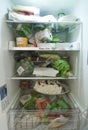 Open refrigerator filled with food in kitchen