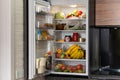 Open refrigerator full of products in kitchen Royalty Free Stock Photo