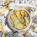 Open retro pocket watch on pile of spare parts