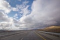 Asphalt road and bright blue sky with fluffy clouds . Empty desert asphalt road from low angle with mountains and clouds on Royalty Free Stock Photo