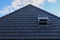 Open roof window in velux style with black roof tiles