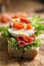 Open sandwich with prosciutto, mozzarella and tomatoes on kitchen table